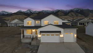 View of front of home with board and batten siding, covered porch, driveway, stone siding, and a mountain view