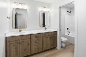 Bathroom with double vanity, light wood-style floors, and  shower combination
