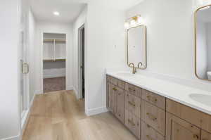 Full bathroom featuring a spacious closet, light wood-style floors, double vanity, a shower stall, and recessed lighting