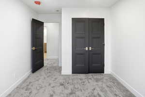 Unfurnished bedroom with light colored carpet and a closet