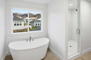 Full bathroom with a stall shower, wood finished floors, and a freestanding bath