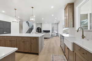 Kitchen with brown cabinets, decorative light fixtures, light stone countertops, and recessed lighting