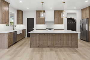 Kitchen with tasteful backsplash, appliances with stainless steel finishes, decorative light fixtures, a kitchen island, and recessed lighting
