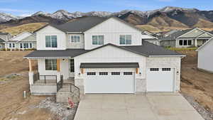 Modern farmhouse featuring board and batten siding, stone siding, a mountain view, a shingled roof, and a porch