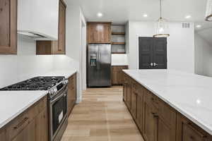 Kitchen with stainless steel appliances, open shelves, ventilation hood, pendant lighting, and light wood-style flooring