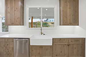 Kitchen with dishwasher, decorative backsplash, light brown cabinetry, and light stone counters