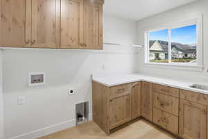 Laundry area featuring light wood-style flooring, cabinet space, washer hookup, electric dryer hookup, and a residential view
