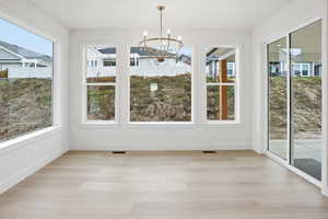 Unfurnished dining area featuring light wood finished floors and a chandelier
