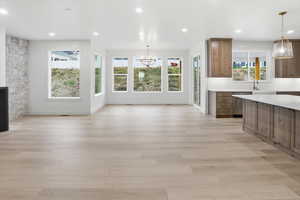 Unfurnished living room featuring a chandelier, light wood-style floors, and recessed lighting