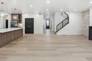 Kitchen featuring open shelves, stainless steel fridge, recessed lighting, light wood finished floors, and pendant lighting