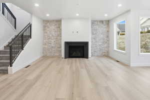Unfurnished living room with recessed lighting, light wood-style floors, stairs, and a fireplace