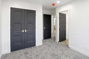 Unfurnished bedroom with a closet, light carpet, and recessed lighting
