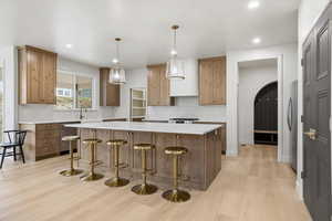 Kitchen with arched walkways, decorative light fixtures, a kitchen bar, light stone counters, and stainless steel appliances