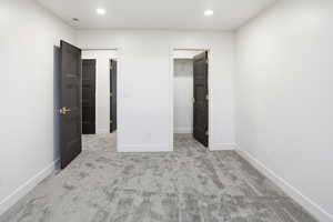 Unfurnished bedroom with light carpet, a walk in closet, and recessed lighting