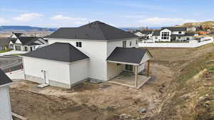 Back of property with a patio area, a mountain view, roof with shingles, and a residential view