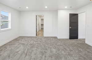 Unfurnished bedroom with light carpet, recessed lighting, and a walk in closet