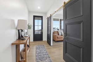 Entrance foyer with a barn door and light wood finished floors