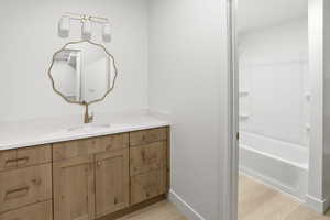Bathroom with vanity, light wood-style flooring, and bathing tub / shower combination