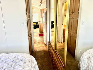 Bedroom featuring freestanding refrigerator, a closet, and dark colored carpet