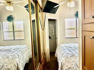 Bedroom with a ceiling fan, dark carpet, and vaulted ceiling