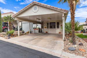 View of front of property with stucco siding, a tiled roof, and a carport