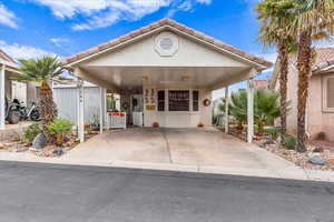 View of front of home with stucco siding, a tile roof, and an attached carport