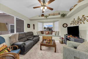 Carpeted living room featuring vaulted ceiling and ceiling fan