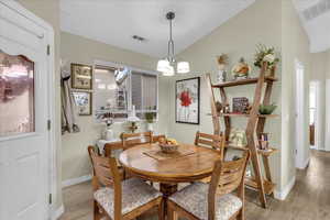 Dining space with a chandelier, light wood-style floors, and lofted ceiling