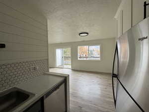 Kitchen with stainless steel appliances, light wood-style flooring, and backsplash