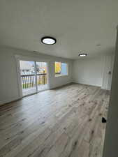 Unfurnished room with a textured ceiling, plenty of natural light, and light wood-style flooring