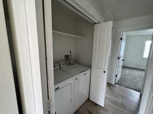 Laundry area with light wood finished floors, independent washer and dryer