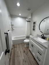 Full bath with vanity, dark wood-type flooring, shower / tub combo with curtain, a textured ceiling, and recessed lighting