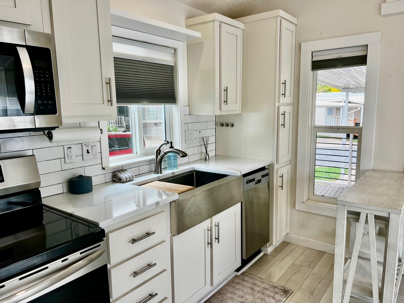 Kitchen with appliances with stainless steel finishes, white cabinets, backsplash, and healthy amount of natural light