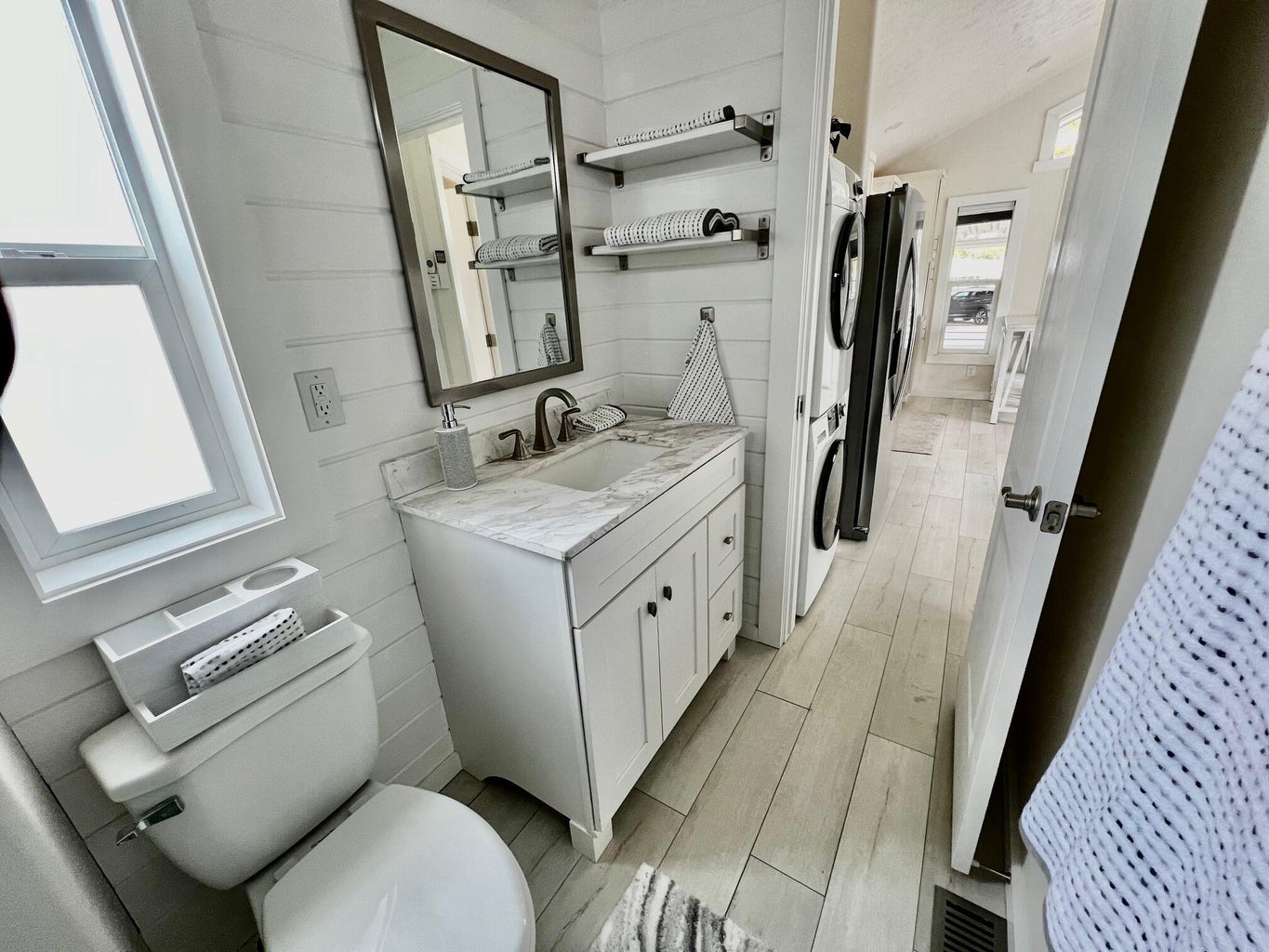 Bathroom featuring vanity, stacked washer / drying machine, lofted ceiling, wood tiled floors, and wood walls
