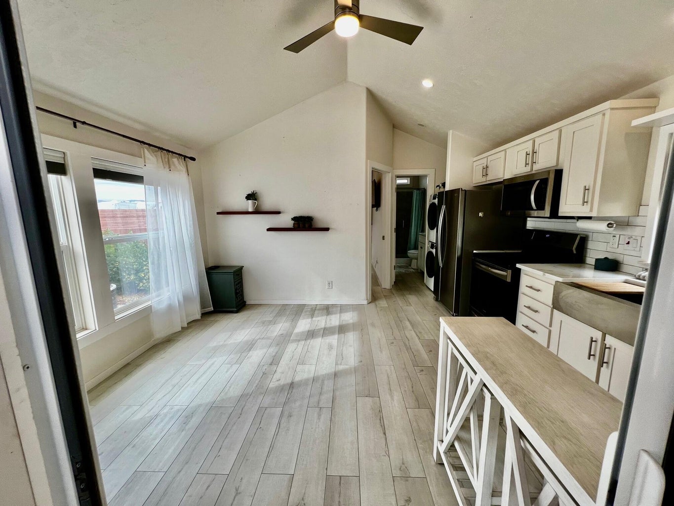 Kitchen featuring white cabinetry, light countertops, vaulted ceiling, black range with electric cooktop, and light wood-style floors