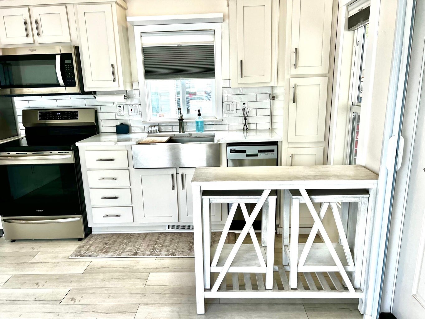 Kitchen featuring stainless steel appliances, white cabinetry, decorative backsplash, and light wood-style flooring