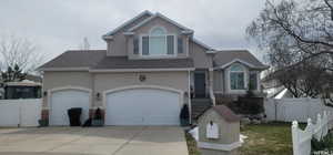 View of front of house with stucco siding, roof with shingles, driveway, and a gate