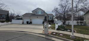 Traditional home with stucco siding, driveway, an attached 3 car garage, stone siding, and roof with shingles