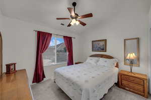 Carpeted bedroom with lofted ceiling and ceiling fan