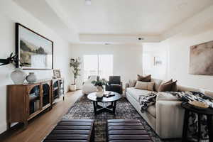 Living room featuring wood finished floors, a tray ceiling, and recessed lighting