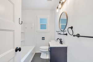 Full bathroom featuring vanity, washtub / shower combination, and dark tile patterned flooring