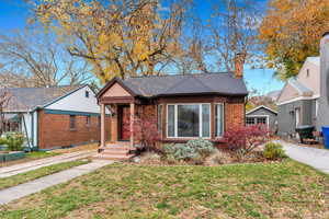 View of front of home featuring a front lawn, brick siding, a chimney, and roof with shingles