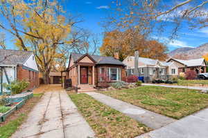Bungalow-style house featuring a front yard, brick siding, a chimney, a residential view, and a mountain view