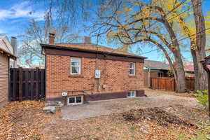 Back of house featuring a fenced backyard, a chimney, brick siding, and a patio