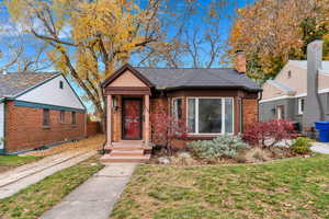 Bungalow featuring a front lawn, brick siding, and a chimney