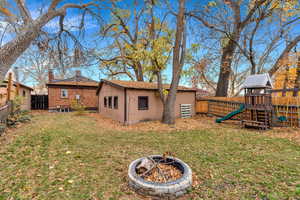 Fenced backyard featuring a playground, an outdoor fire pit, and an outdoor structure