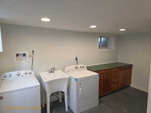 Laundry room featuring recessed lighting, concrete flooring, and washer and dryer