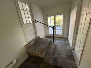 Entryway with a textured wall and stone tile flooring