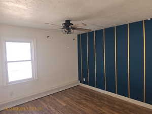 Unfurnished room featuring a baseboard heating unit, dark wood-type flooring, a ceiling fan, and a textured ceiling