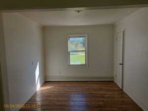 Unfurnished room featuring dark wood-type flooring, a baseboard radiator, and ornamental molding